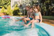 © ADDICTIVE STOCK - Happy children sitting at poolside and splashing water on sunny day