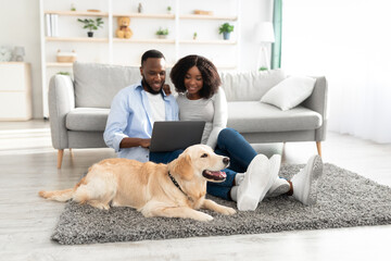 Wall Mural - Black couple at home using laptop relaxing with dog