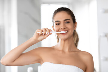 Sticker - Headshot Of Lady Brushing Teeth Looking At Camera In Bathroom