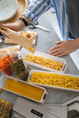 Wall Mural - Top view female housewife placing sorting different kinds of vegan pasta into pp boxes