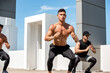 © Atstock Productions - Group of fit sports men doing squat bodyweight workout training outdoors on building rooftop in sunlight - exercisse in the open air concept