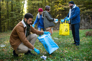 Diverse group of volunteers cleaning up forest from waste, community service concept