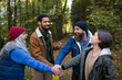 © Halfpoint - Diverse group of happy volunteers stacking hands together after cleaning up forest.