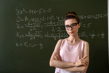  college female student writing on blackboard  completing mathematical equations