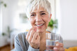 © Graphicroyalty - Head shot portrait happy woman holds pill glass of water, takes daily medicine vitamin D, omega 3 supplements, skin hair nail strengthen and beauty, medication for health care concept