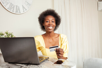 beautiful African American black woman uses a bank card to Shopping online. Delivery of goods to house. laptop on table. smiling, happy