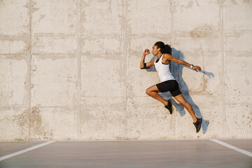 Wall Mural - Black sportswoman listening music while working out on parking