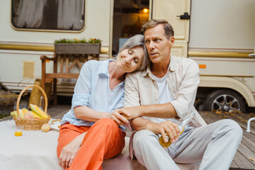 White couple holding hands and hugging while having picnic by trailer