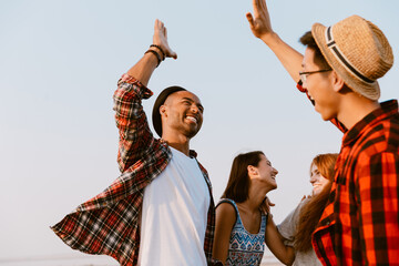 Young multiracial friends making fun while giving high five