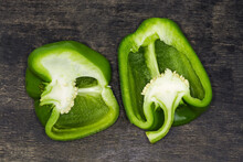 Two Green Bell Peppers Halves, Cut Lengthwise On Dark Surface