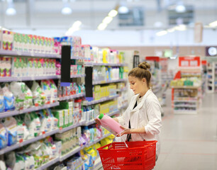 Wall Mural - Woman shopping in supermarket reading product information.woman choosing laundry detergent in supermarket