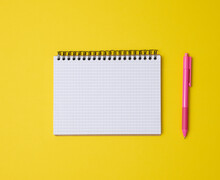 Open Notebook In A Cage With White Blank Sheet And On A Yellow Background, Top View