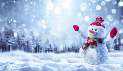 Wall Mural - snowman on snow in forest with snowfall in defocused landscape