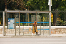 Woman In Trench Coat Waiting At Bus Stop