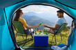 © New Africa - Couple and cool box with bottles of beer in mountains, view from tent