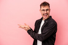 Young Caucasian Man Isolated On Pink Background Holding A Copy Space On A Palm.