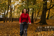 Smiling Woman Cycling At Autumn Park