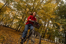 Smiling Woman Cycling In Autumn Park
