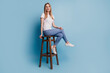 Portrait of cheerful positive charming blonde woman sit chair look camera wear white t-shirt isolated on blue color background