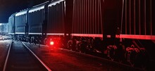 Large Cargo Train With Goods Leaving The Terminal At Night, Wagons (containers) Close-up. Concept Urban Scene. Illumination, Red Light. Freight Transportation, Industry, Business, Logistics, Delivery
