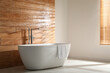White bathtub with towel near wooden wall in room