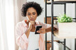 © Syda Productions - technology and people concept - woman with smartphone standing at shelf at home