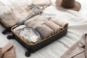 Wall Mural - Open suitcase with folded clothes, shoes and accessories on bed