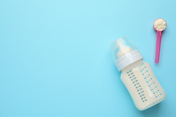 Wall Mural - Feeding bottle with infant formula and powder on light blue background, flat lay. Space for text