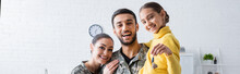 Happy Family In Military Uniform Holding Daughter With Key At Home, Banner