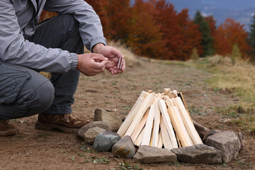 Wall Mural - Man making bonfire outdoors, closeup. Camping season