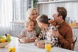 © LIGHTFIELD STUDIOS - happy couple looking at each other and hugging sons during breakfast