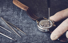 Watchmaker working with screwdriver in vinyl gloves working to repair wristwatches, macro photography, retro style