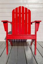 Bright Red Adirondack Chair On Rural Porch.