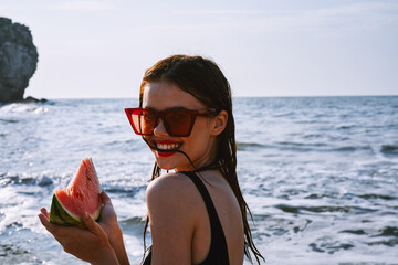 Wall Mural - pretty woman in a black swimsuit with a watermelon in her hands summer Ocean