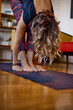 © chika_milan - A flexible woman is standing on a yoga mat and practicing yoga.