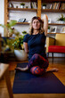 © chika_milan - A flexible woman is sitting on the yoga mat at home in Shoelace yoga posture and meditating.