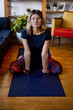 © chika_milan - A flexible woman is sitting wide-legged and practicing yoga at home.