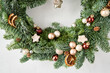 Beautiful festive wreath of fresh spruce on Gray wall. Xmas circlet with ornaments and balls. Christmas mood.