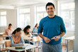© Drazen - Portrait of happy high school teacher in the classroom looking at camera.