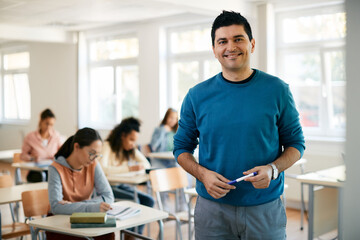 Portrait of happy high school teacher in the classroom looking at camera.
