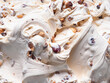 Frozen Hazelnut flavour gelato - full frame detail. Close up of a white creamy surface texture of Ice cream filled with pieces of nuts.