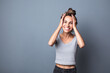 © BestForYou - Happy excited charming woman holding her head on gray studio background.