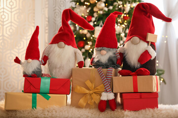 Cute Christmas gnomes and gift boxes on carpet in room