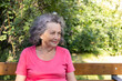 © Darya - Elderly woman with gray hair in the park. Granny with wrinkles and freckles on her face smiling looking to the side
