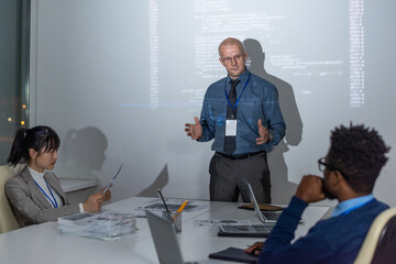 Poster - Confident mature coach or it-engineer making presentation to young intercultural subordinates or colleagues
