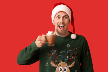 Sticker - Surprised young man with cup of hot cocoa on color background