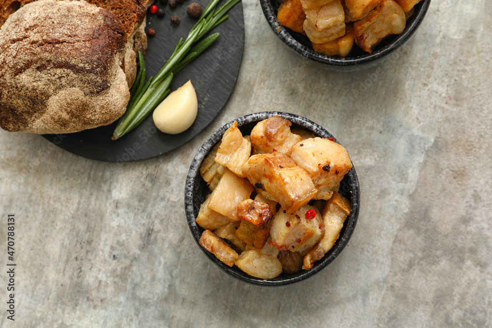 Bowls with tasty cracklings and bread on grunge background