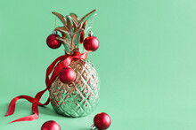 Metal Pineapple Decorated With Red Christmas Balls On Green Background. Alternative Christmas Tree
