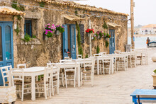 Picturesque Village Of Marzamemi, In The Province Of Syracuse, Sicily - Tables And Chairs Setup In Traditional Italian Restaurants In The Main Square Of The Historic Village During A Sunny Day.
