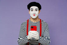 Charismatic Amazing Fun Young Mime Man With White Face Mask Wears Striped Shirt Beret Look Camera Hold In Hand Use Mobile Cell Phone Isolated On Plain Pastel Light Violet Background Studio Portrait.